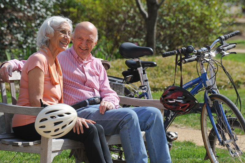 elderly couple on bench with bicycles in background