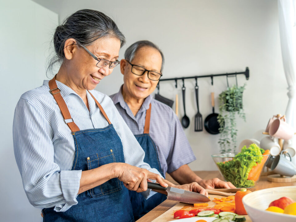 Asian American couple preparing food in kitchen