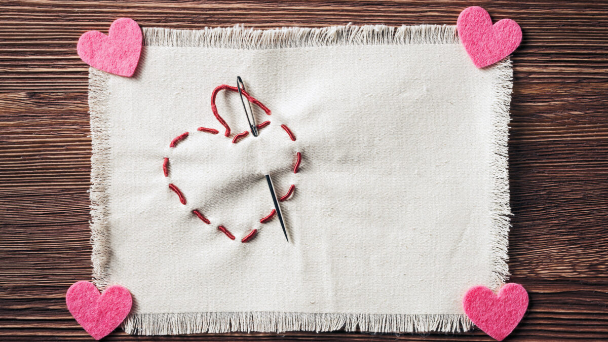 Stitched handmade Valentines heart symbol over wooden background