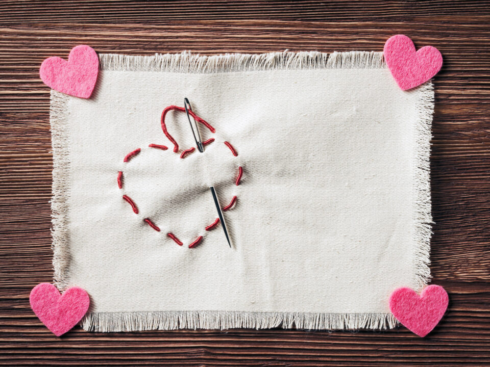 Stitched handmade Valentines heart symbol over wooden background