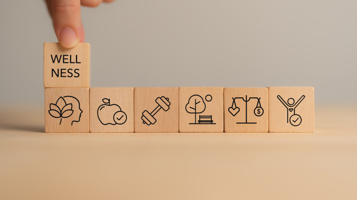 Wooden block with wellness icons, health care ,including mental well-being, fitness, nutrition, sleep, relationships and financial balance.